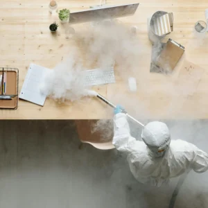 A Person in a Protective Suit Fumigating a Table