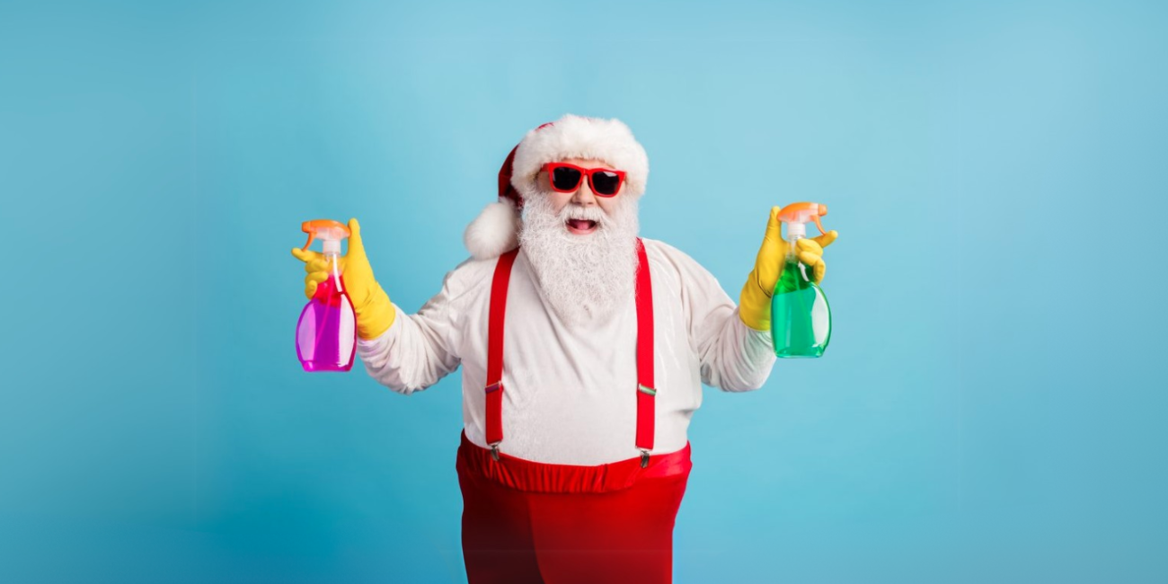 Santa holding cleaning sprays in each hand.