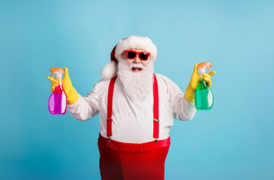 Santa holding cleaning sprays in each hand.