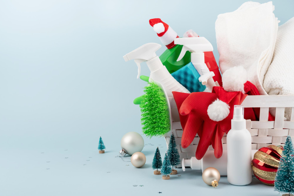 Christmas cleaning tools and decorations in a white laundry basket with a blue background.